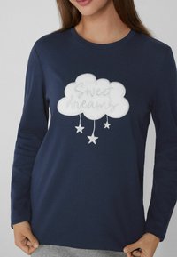 Námořnická košile s dlouhým rukávem, vyšívanými oblaky a hvězdami. Text "Sweet dreams" v kurzívě, měkká látka, uvolněný střih a kulatý výstřih.