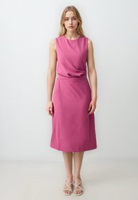 Fuchsia ärmelloses Kleid mit einem drapierten Ausschnitt, glatter Textur und Midi-Länge, kombiniert mit leichten Riemchensandalen.