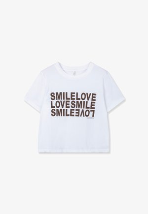 White cotton cropped t-shirt featuring bold, repeating text "SMILE LOVE" in brown. Simple crew neck and short sleeves.