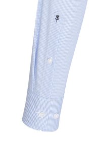 Blauw en wit geblokt overhemelsmouw met twee witte knopen, met zwarte bloembroderie nabij het ellebooggebied. Katoenen stoffen textuur.