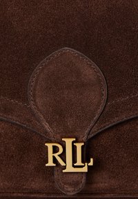 Geantă din suede maro, cu un emblemă "RLL" aurie, design cu clapetă curbă și detalii de cusătură subtile. Textură netedă pe întreaga suprafață.