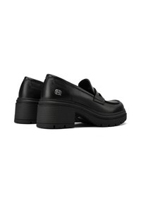 Scarpe piattaforma nere in pelle con punta arrotondata, caratterizzate da una suola testurizzata e un piccolo accento con logo metallico vicino al tallone.
