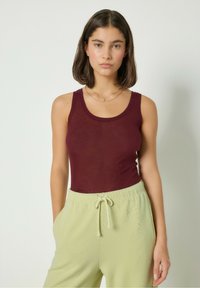 Burgundy linne i lätt tyg med rund halsringning, matchat med ljusgröna, texturerade byxor med dragsko.