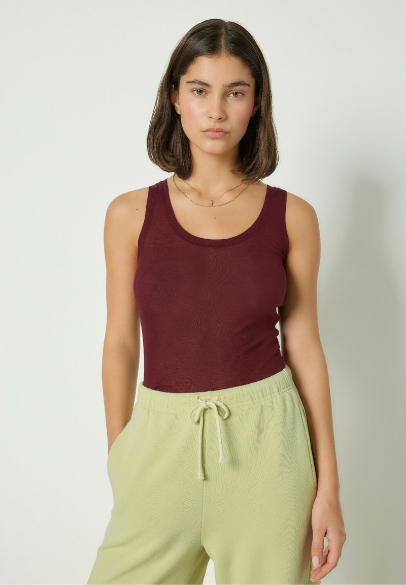 Burgundy linne i lätt tyg med rund halsringning, matchat med ljusgröna, texturerade byxor med dragsko.