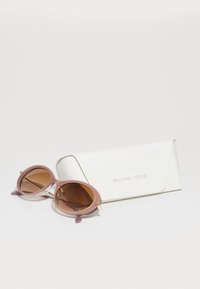 Runde solbriller med en rosa og hvit ramme, brune tonede linser og gullbeslag. Inkluderer et hvitt etui med "MICHAEL KORS" preget.