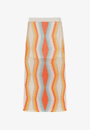 Mujer con una falda maxi de crochet a rayas y colores vibrantes en tonos naranja, azul y amarillo, combinada con sandalias negras con tachuelas.