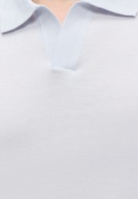 Gros plan sur le col et la partie supérieure de la poitrine d'un polo en maille bleu clair à manches courtes.
