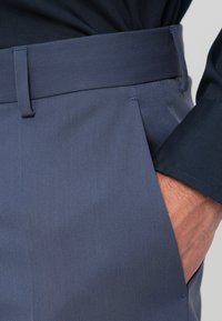 Ναυτικές παντελόνες φόρμας με λεία υφή, με επίπεδο εμπρός μέρος και πλαϊνές τσέπες. Η μέση είναι από υλικό σταθερού ναυτικού χρώματος.