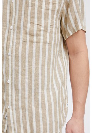 Kortærmet button-up skjorte i beige og hvide striber, med en forlommer og et tekstureret, vævet stof. Hvide knapper synlige.