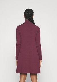 Robe mi-longue à manches longues en tissu bordeaux profond. Dotée d'un col montant et d'une texture lisse, s'évasant légèrement à l'ourlet.