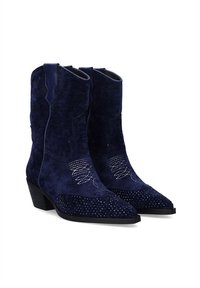 Botas de cowboy azul marino con acabado de ante, punta afilada, tacón bajo y costuras decorativas en blanco, con acentos de strass en la punta.