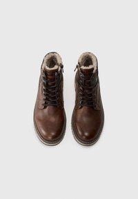 Braune Lederstiefel mit gepolstertem Kragen, Schnürsenkeln, seitlichem Reißverschluss und strukturiertem Profil. Das Innenfutter besteht aus weichem Fell.