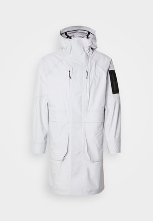 Parka branca impermeável com gola alta, capuz ajustável, dois bolsos frontais e um bolso com fecho de correr na manga. Apresenta um tecido liso e suave.