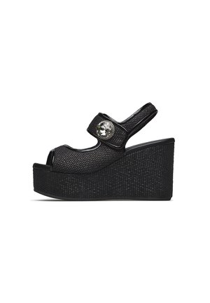 Sandalo con zeppa nero con cinturini texturizzati, punta aperta, cinturino sul tallone e una grande gemma decorativa trasparente sulla fascia anteriore.