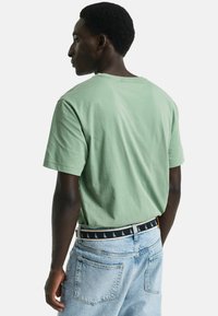Hellblaue Jeans und ein gemusterter Gürtel.