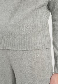 Graues Strickoutfit mit strukturiertem Strickmuster. Dezente "A|X" Stickerei auf Ober- und Unterteil. Weicher Stoff mit sauberem Finish.