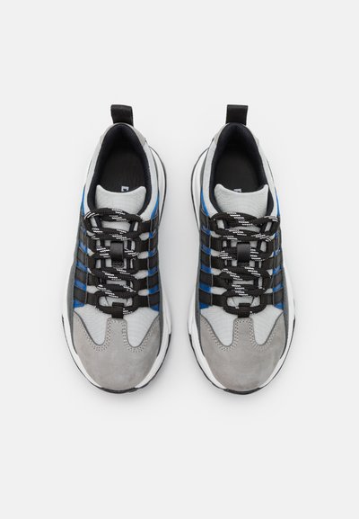 Scarpe sportive con tomaia in suede grigio e mesh, dettagli neri e blu, lacci texturizzati e una spessa suola in gomma bianca.