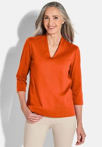 V-hals, driekwartmouwen top in een felle oranje kleur, gemaakt van een zachte stof met een comfortabele pasvorm. Eenvoudig ontwerp, zonder patronen of zichtbare hardware.