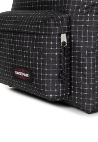 Svart textilryggsäck med ett kvadratiskt rutmönster i grått, en framficka med dragkedja och en Eastpak-logotyp på nedersta högra hörnet.