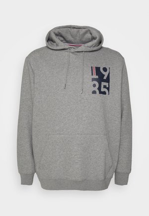Grauer Kapuzenpullover mit Fronttasche, Kordeln und einem marineblauen Schriftzug "1985" mit kleinem roten Text auf der oberen linken Brust.