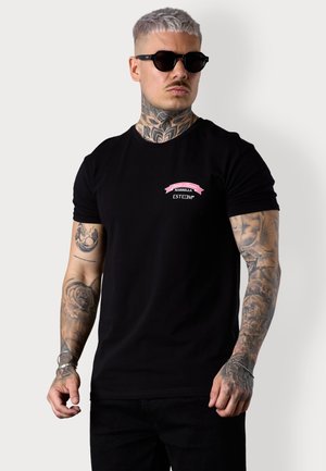 Schwarzes T-Shirt mit kurzen Ärmeln und rundem Ausschnitt, das ein rosa und weißes Logo-Detail auf der Brust aufweist. Weicher Stoff, taillierter Schnitt.