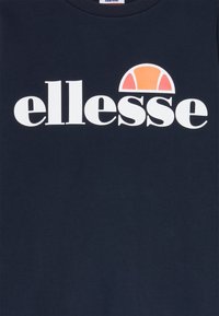 Sudadera navy con un gran logo blanco de "ellesse". Presenta un acento mitad naranja y mitad rojo sobre el logo, fabricado en un material de algodón suave.