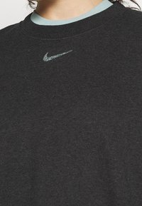 Gros plan d'un sweat-shirt Nike gris foncé avec un petit logo Nike Swoosh multicolore centré sous l'encolure.