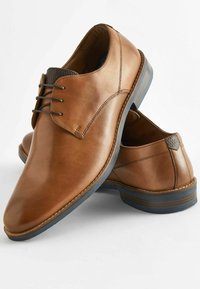 Zapatos de cuero marrón con un acabado suave, diseño tradicional de cordones y acentos en el talón de textura contrastante. Suela de goma con ranuras sutiles.