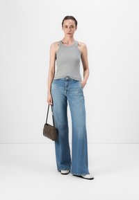 Grå ermeløs topp parret med høyt liv, lyseblå flarejeans. Tilbehør inkluderer en liten brun håndveske og hvite sko.