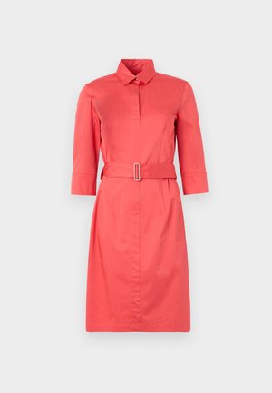 Robe chemise de couleur corail avec un col, des manches trois-quarts, une taille cintrée par une ceinture et des boutons sur le devant. Texture lisse.