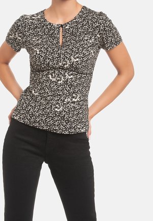 Musta kukkakuvioinen pusero, jossa on lyhyet hihat, avainreikäkaulus, istuva leikkaus ja teksturoitu kangas, jossa valkoiset kukkakuviot. Mustat housut.