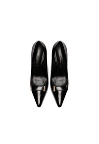 Alte scarpe col tacco in vernice nera con punta affusolata e dettagli dorati. Superficie liscia e design elegante. Nome del marchio visibile all'interno.