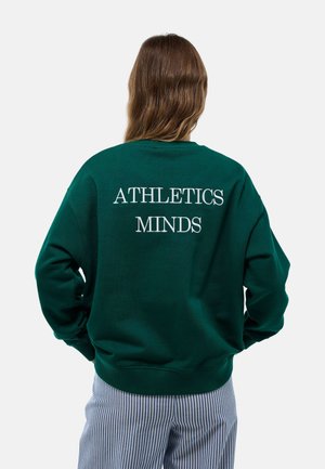 Sweatshirt vert avec une coupe décontractée, présentant un texte brodé blanc "ATHLETICS MINDS" au dos. Poignets et ourlet côtelés.