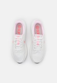 Zapatos deportivos blancos con acentos en rosa, parte superior de malla, cordones y collar acolchado. Logo notable en las plantillas y el costado. Suela de goma.
