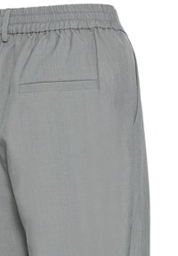 Pantalon gris sur mesure avec une texture lisse, doté d'une taille élastiquée et d'une seule poche à l'arrière. Design simple, porté polyvalent.