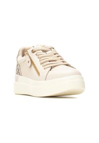Zapatilla beige con un upper de cuero suave, acentos texturizados, cierre de cordones, cremallera lateral decorativa y suela de plataforma blanca.