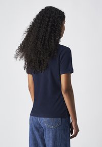 T-shirt à manches courtes bleu marine en coton doux, avec une coupe classique, une texture lisse et un ourlet droit, associé à un jean en denim bleu.