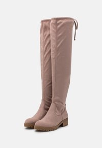 Botas altas, de color rosa empolvado y por encima de la rodilla, con una textura suave y aterciopelada y un tacón bajo y grueso. Cuenta con un cordón para un ajuste ajustable.