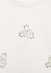 Felpa bianca con decorazioni metalliche e gioielli distribuiti in vari colori e forme, che aggiungono dettaglio alla texture del tessuto.