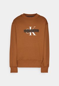 Sweat-shirt marron à col rond avec poignets et ourlet côtelés, arborant le logo blanc "cK" et le logo noir "Calvin Klein Jeans" sur la poitrine.