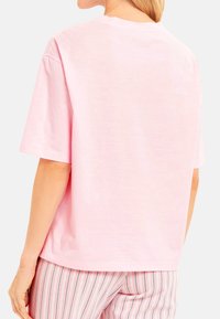 Roze T-shirt met korte mouwen van zacht materiaal, met een ontspannen pasvorm en een eenvoudige ronde hals. Gladde textuur zonder patronen.