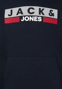 Felpa blu navy con tasca frontale, caratterizzata da un design a strisce bianco e rosso con il testo "JACK & JONES" in lettere grasse.