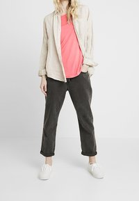 Světle lněná košile na knoflíky, neonově růžové tričko, tmavě šedé kalhoty s manžetami a bílé tenisky. Neformální outfit s volnějším střihem.