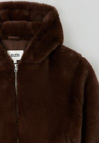 Veste en fausse fourrure marron avec capuche, fermeture éclair et texture douce. Étiquette indiquant la marque "BZB" et la taille "S". Doublure intérieure lisse.