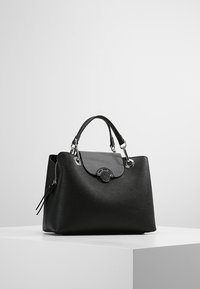 Bolso de mano de cuero negro con diseño estructurado, con asa superior, herrajes plateados y textura suave. Detalle de cremallera en el lateral.
