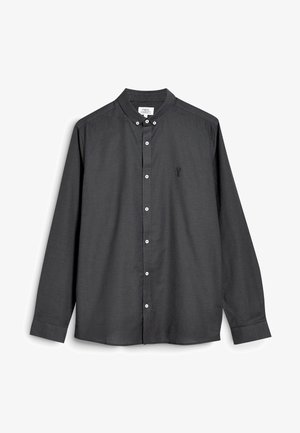 Chemise gris foncé à boutons pression avec col mao, manches longues et boutons blancs. Présente un petit motif brodé sur la poitrine.