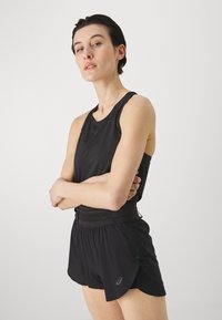Top sportivo nero senza maniche abbinato a pantaloni corti neri con pannello in rete e orlo curvo. Tessuto leggero.
