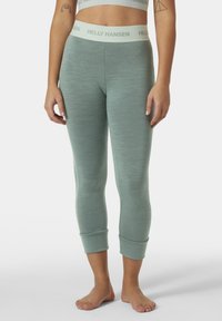 Lichtgroene, strakke leggings van een gestructureerde stof met een brede tailleband waarop "HELLEY HANSEN" in lichtbeige is gedrukt. Enkel-lengte ontwerp.