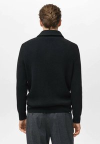 Maglione nero lavorato a maglia con colletto a scialle, texture a costine e maniche lunghe. La vista posteriore mostra una silhouette aderente e un design minimale.