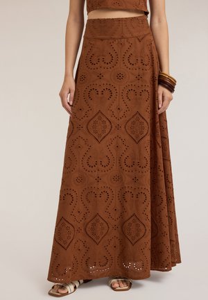 Lange bruine rok met een textuurpatroon en uitsnijdingen, een aansluitende taille en een vloeiende silhouet. Gecombineerd met een bijpassende top.